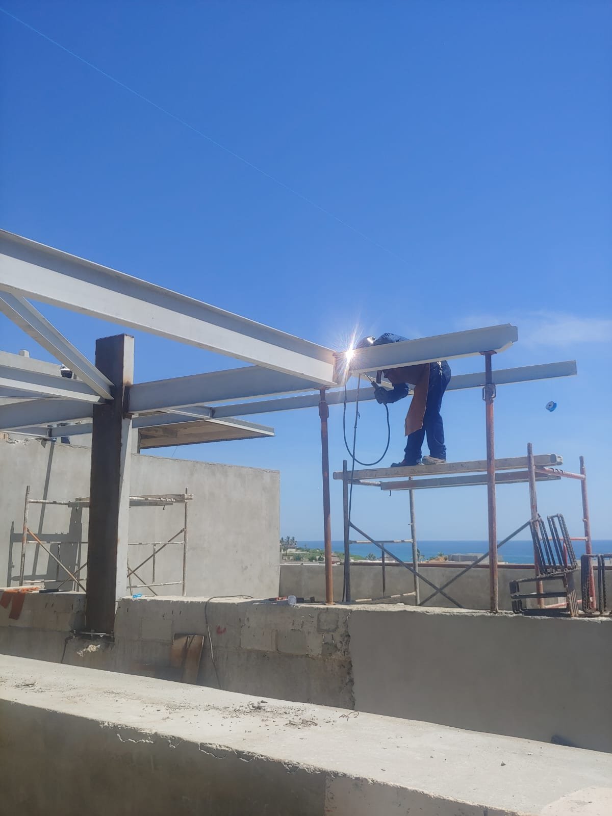 Soldador uniendo vigas de acero sobre andamio