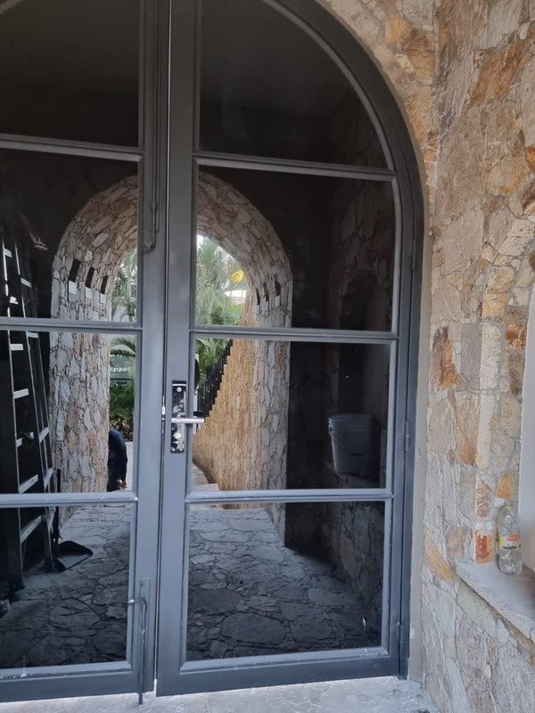 Puerta principal de acero y cristal en arco de cantera