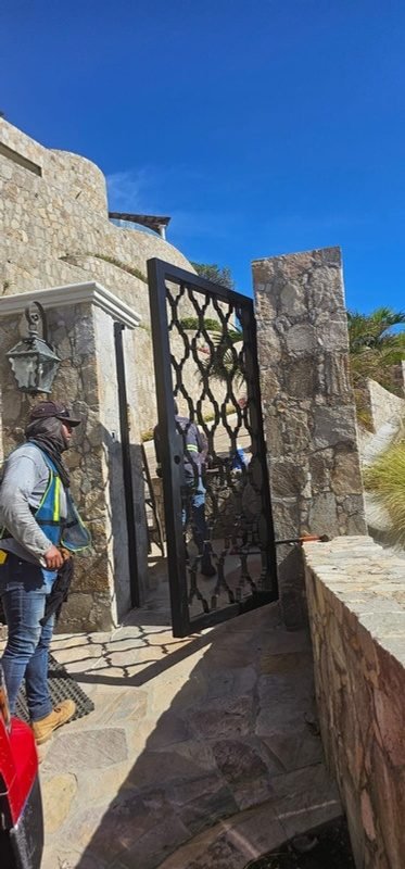 Puerta peatonal de celosía en acceso de piedra
