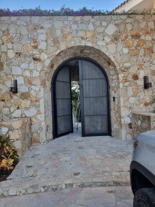 Portón de madera con bastidor de acero en arco de piedra